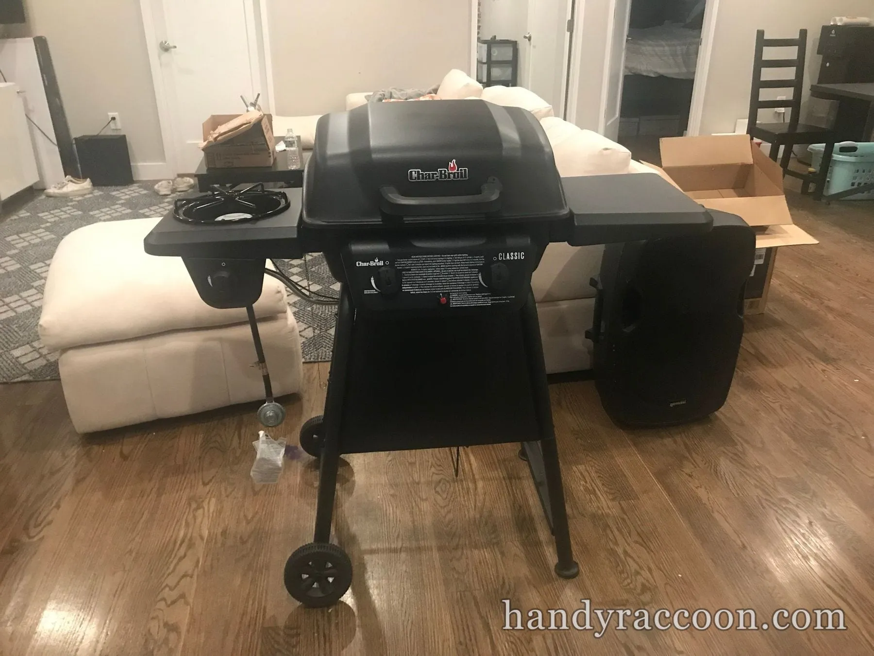 Fully assembled black Char-Broil Classic gas grill with side burner standing on a wood floor indoors.