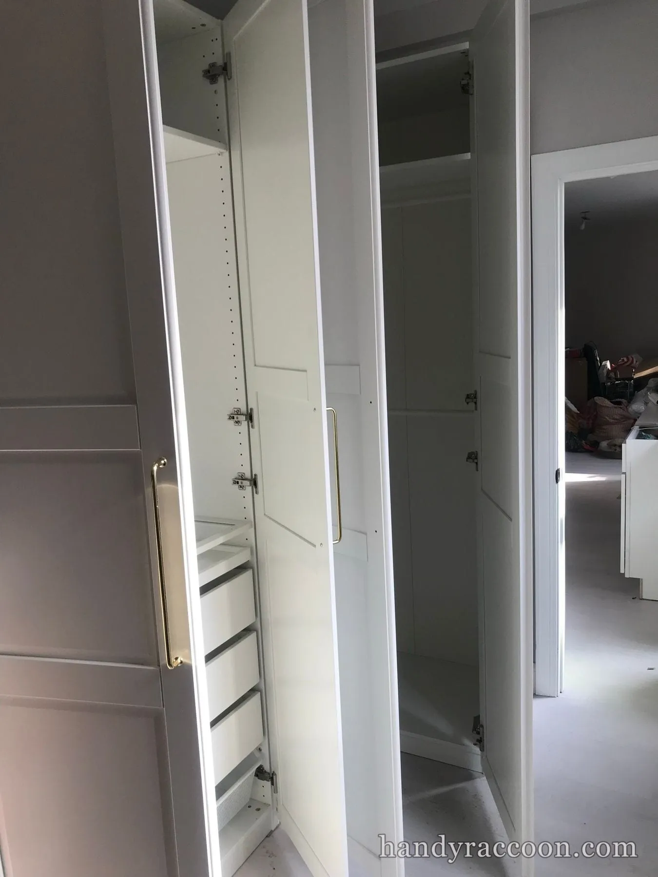 White wardrobe units with brass pull handles and white drawers, doors open in a panelled room