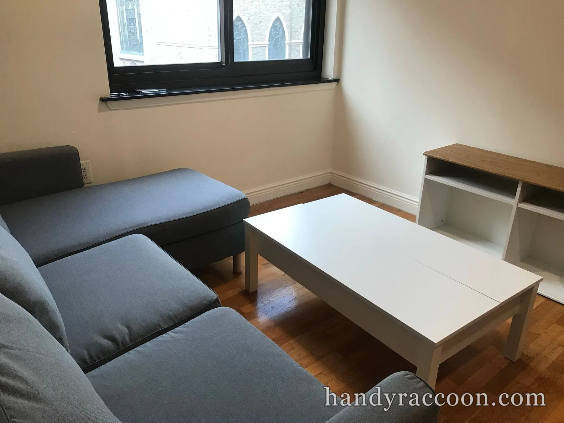 Grey chaise sectional, white rectangular coffee table and white console assembled near a window