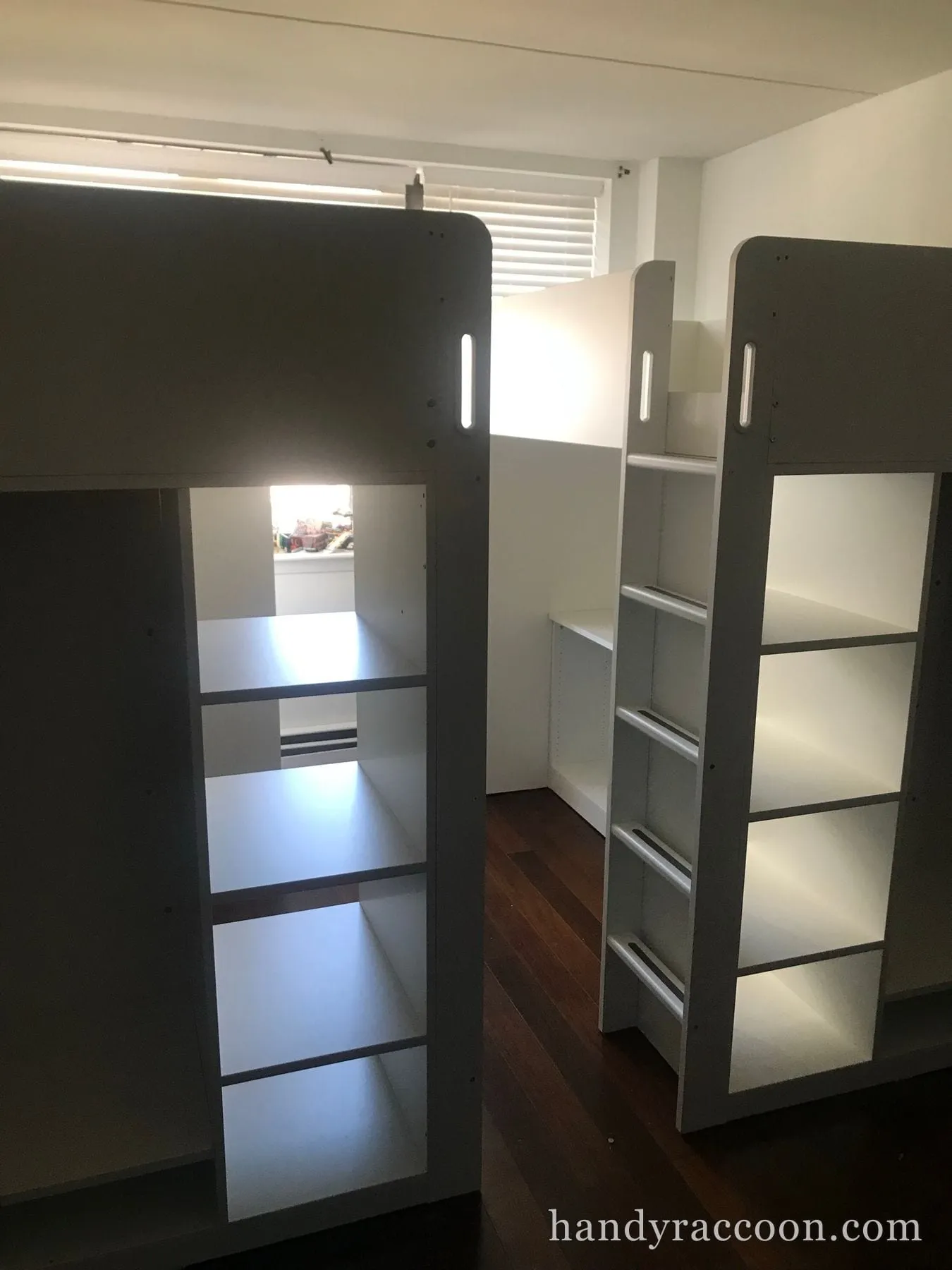Grey loft bed structure with side cube shelving, an integrated ladder and a desk underneath