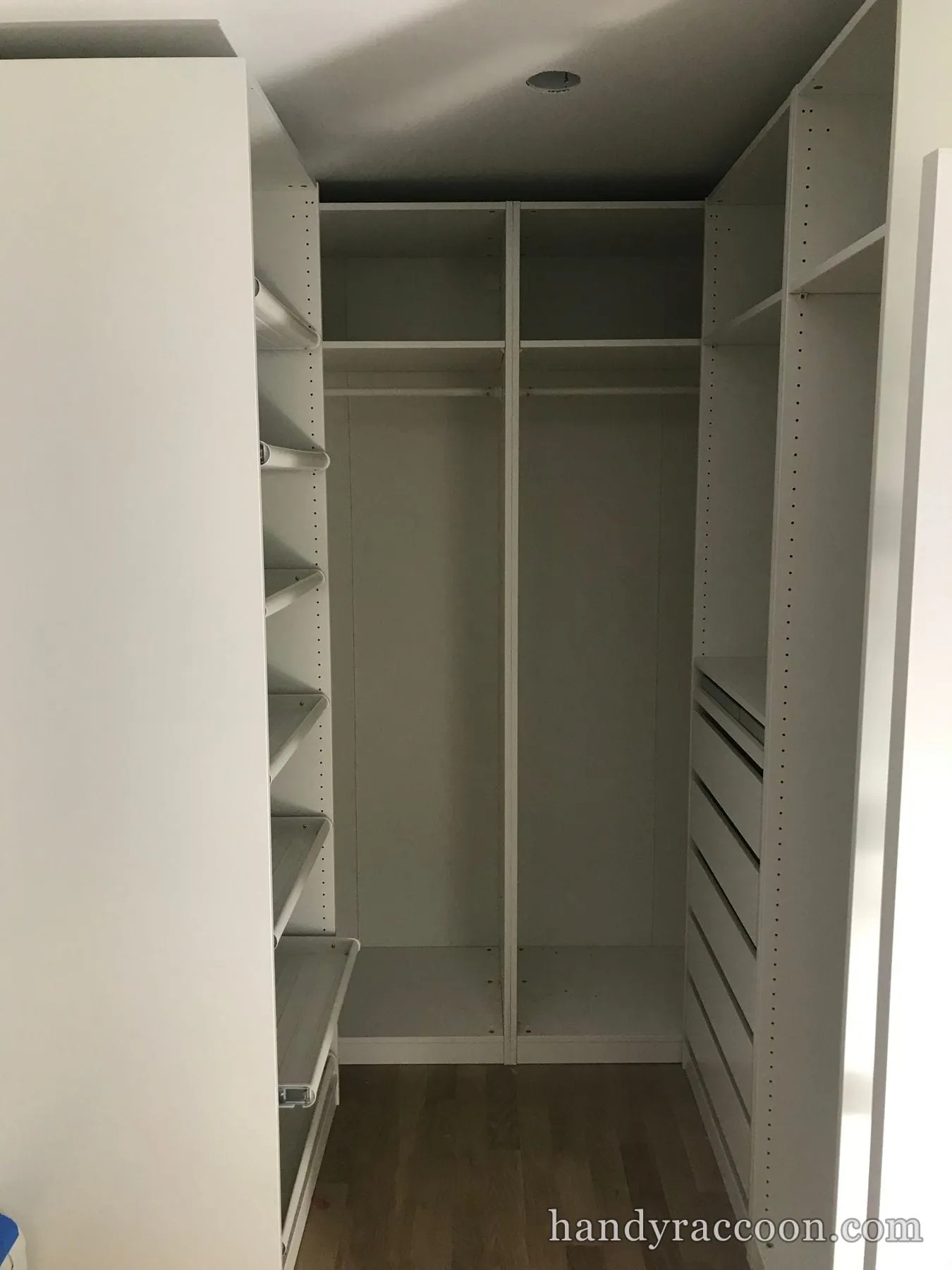 White walk-in closet fitted with hanging rods, angled shoe shelves, and pull-out drawers.