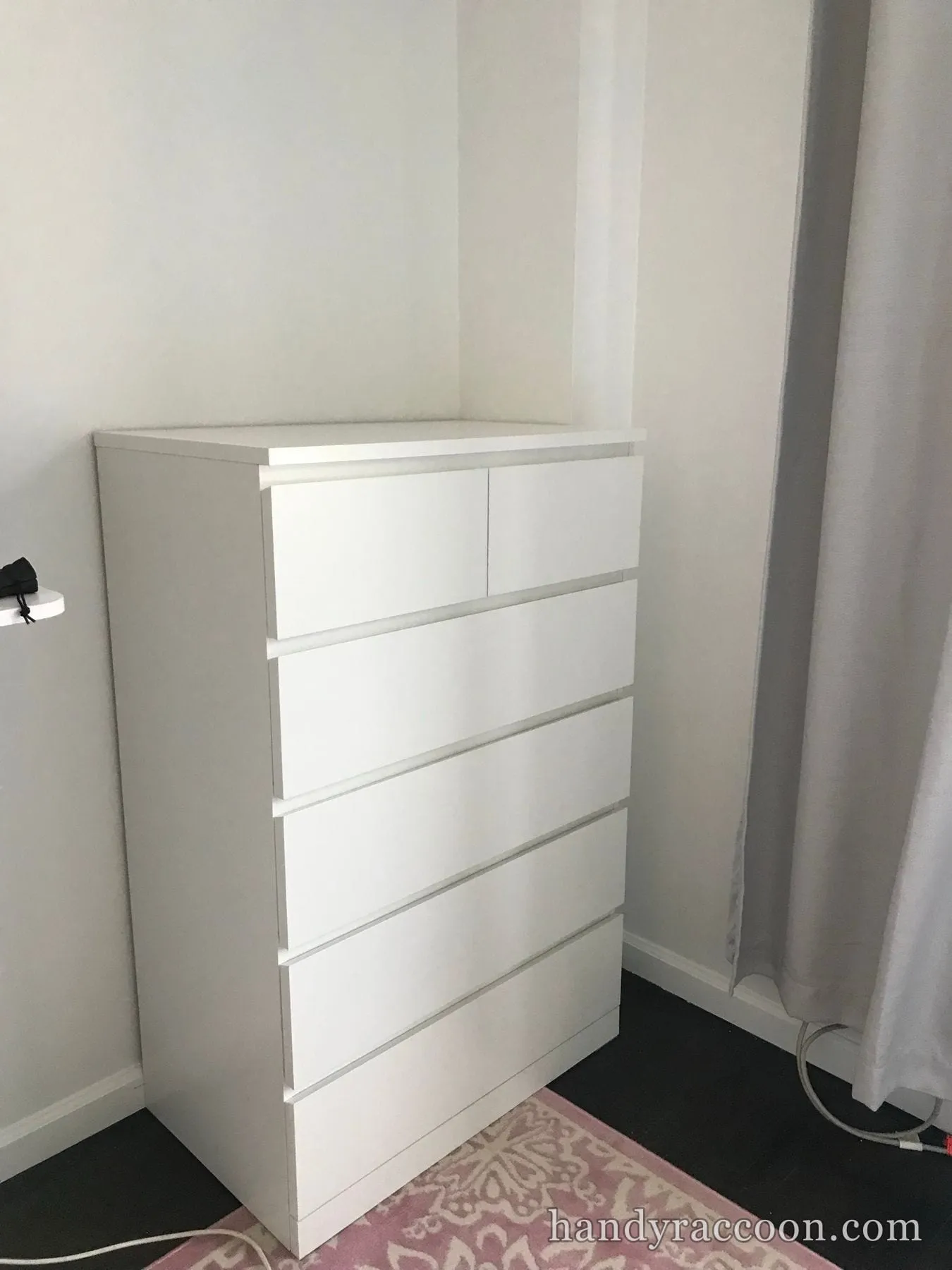 Tall white six-drawer dresser assembled and standing in a bright bedroom corner.