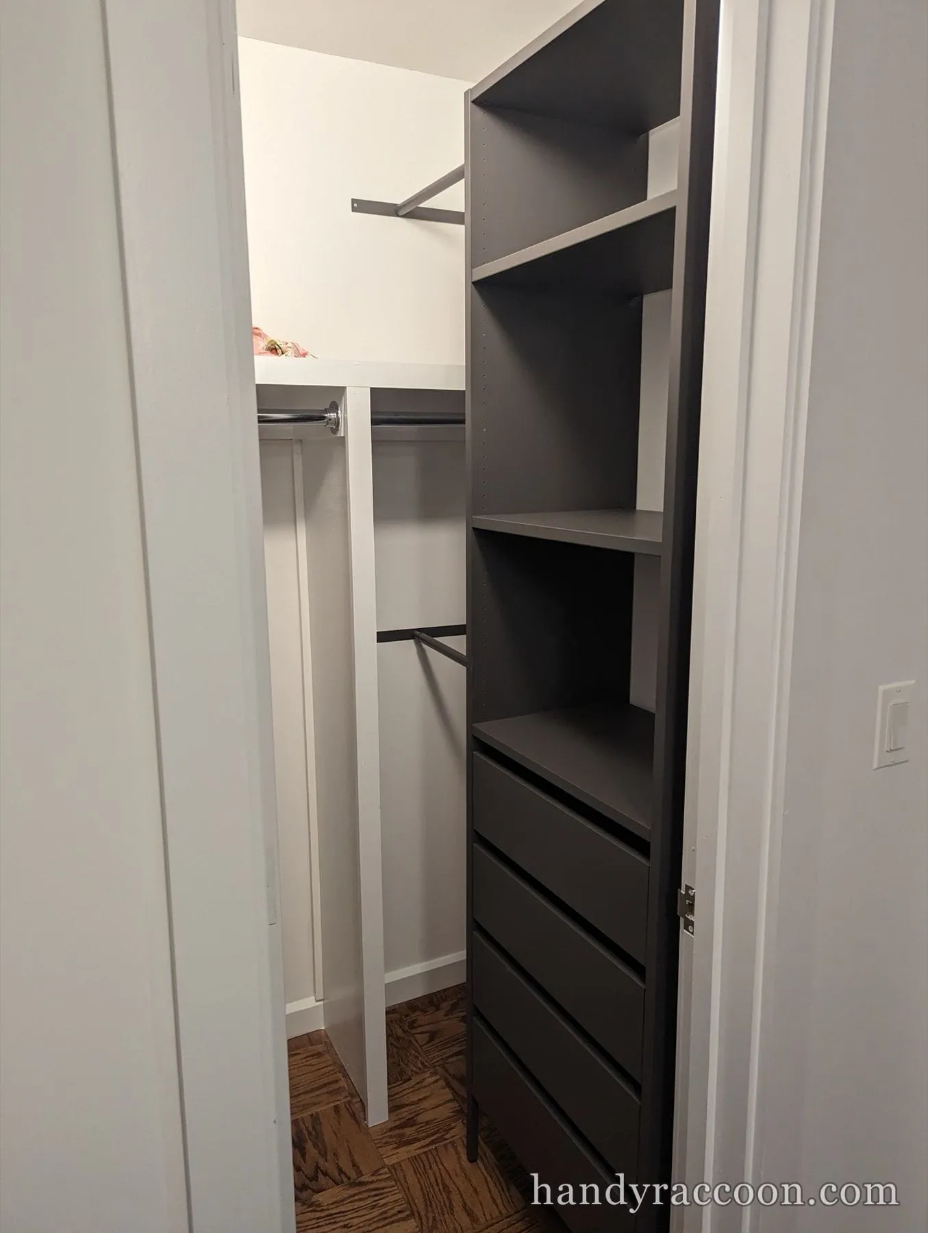 Reach-in closet fitted with a charcoal shelf-and-drawer tower and white clothes rods.