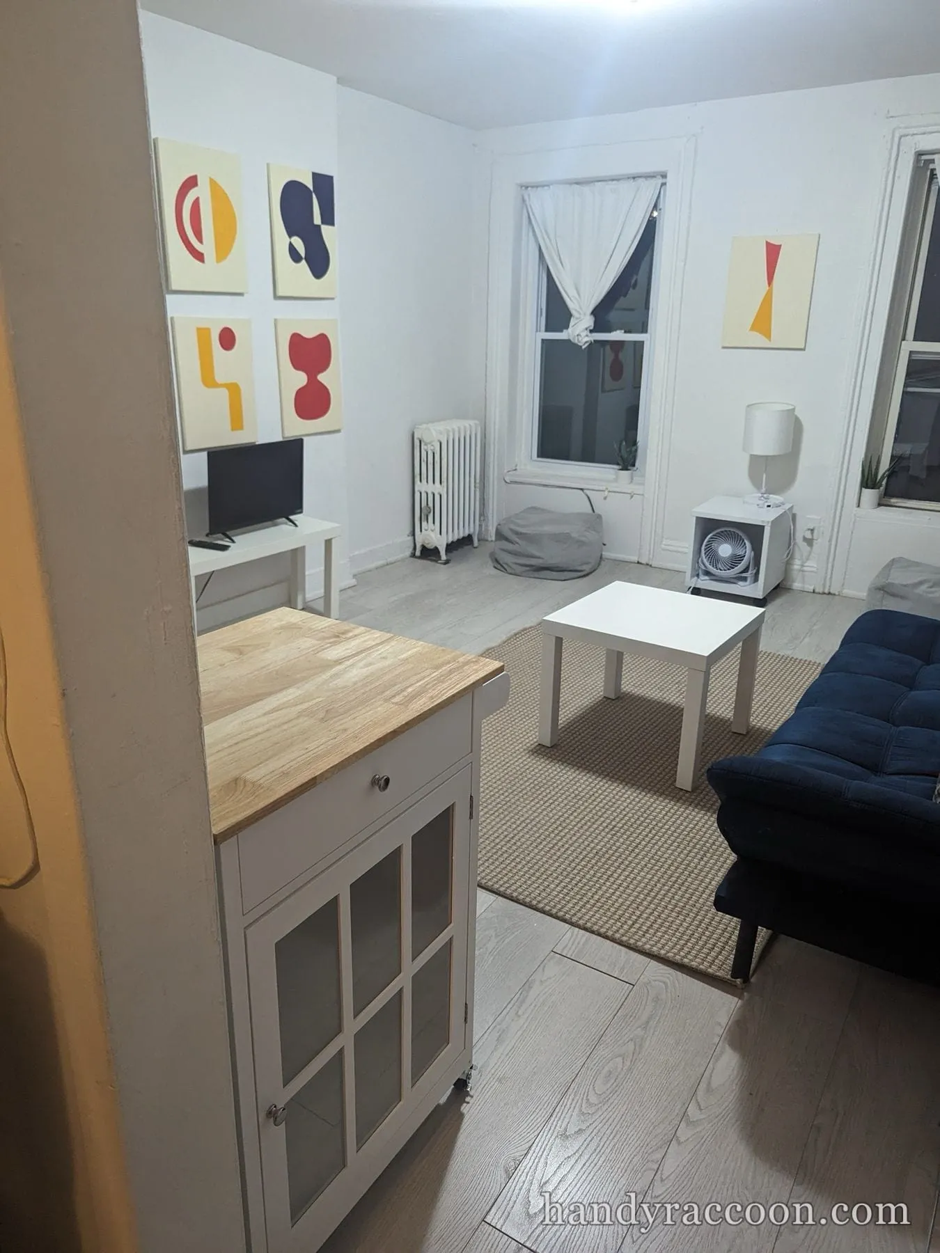White kitchen island cart with wood butcher-block top assembled in a living room at night.