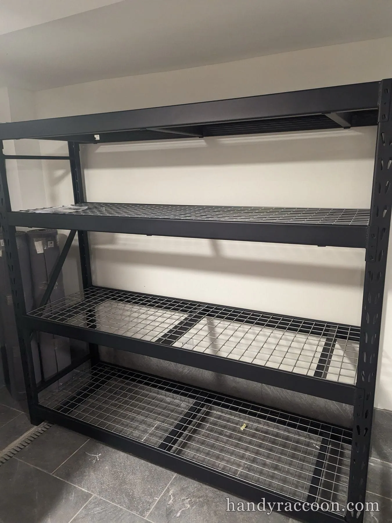 Heavy-duty black metal wire shelving unit assembled against a wall.