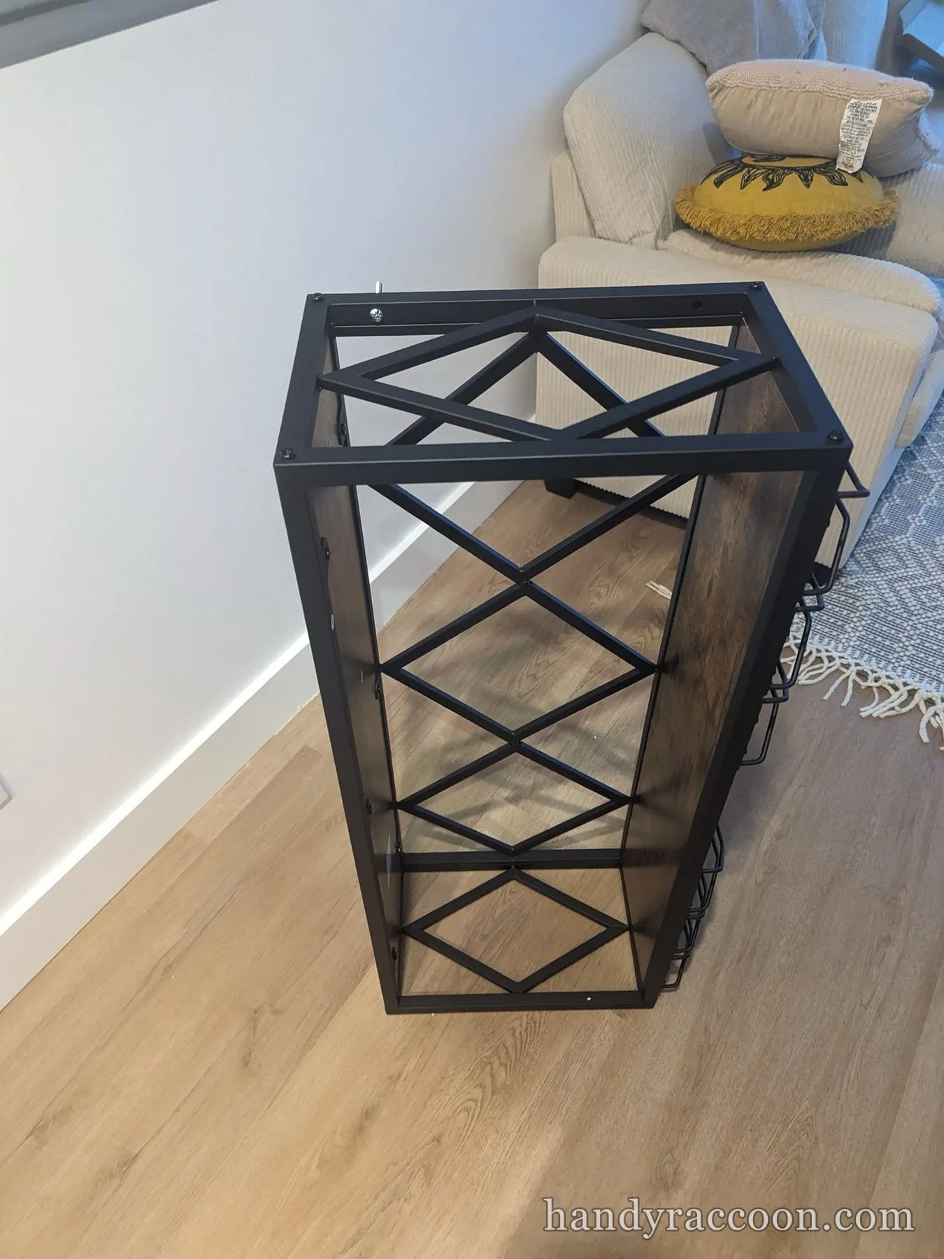 Black metal geometric wine rack with glass holders assembled on the floor.
