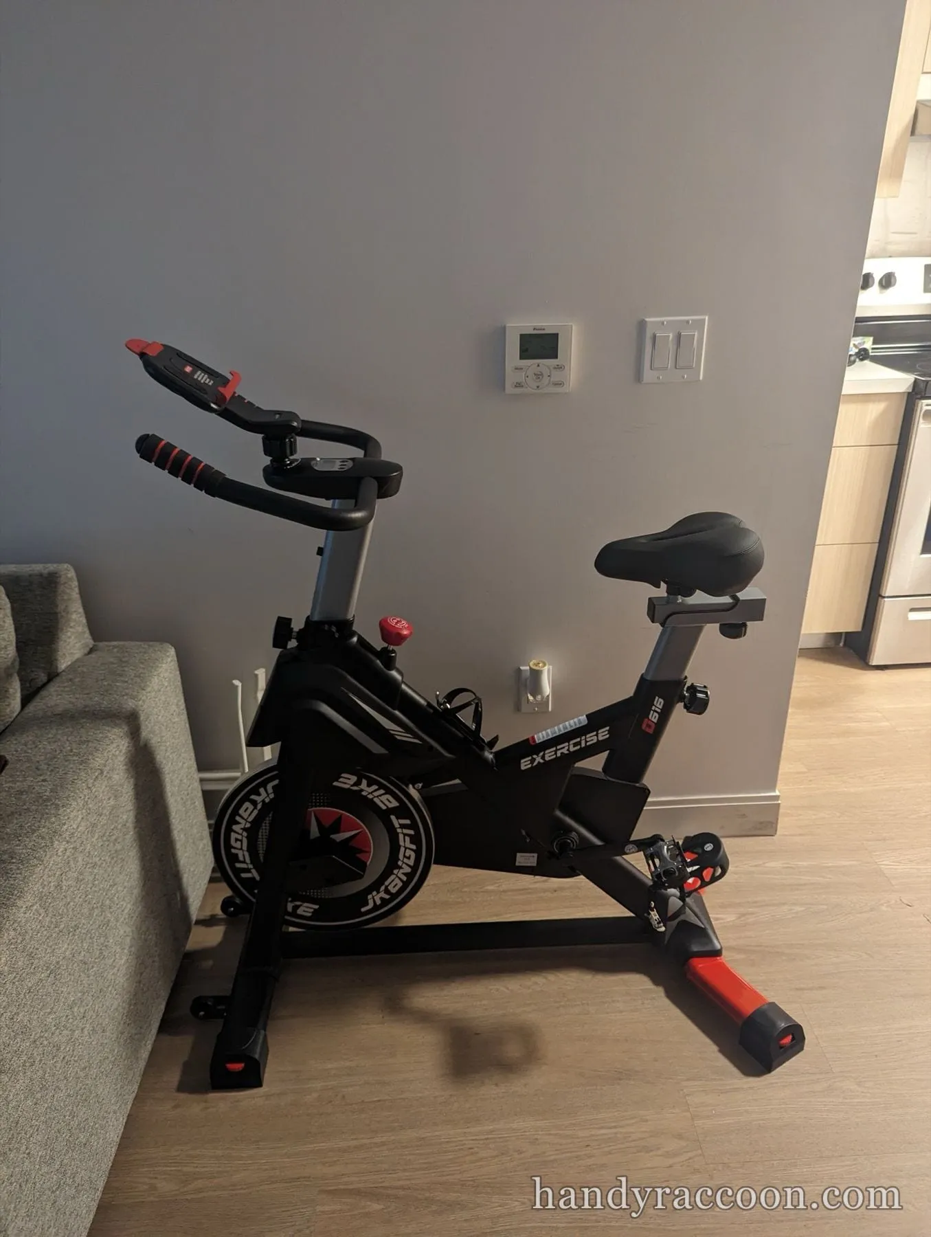 Black and red upright exercise bike assembled on a wood floor in a living room.