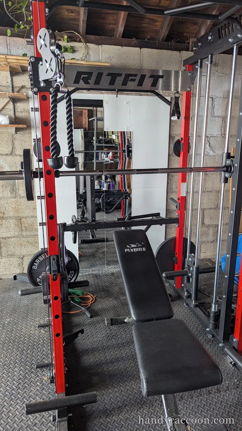 Red and black Smith machine power rack with an adjustable bench in a garage.