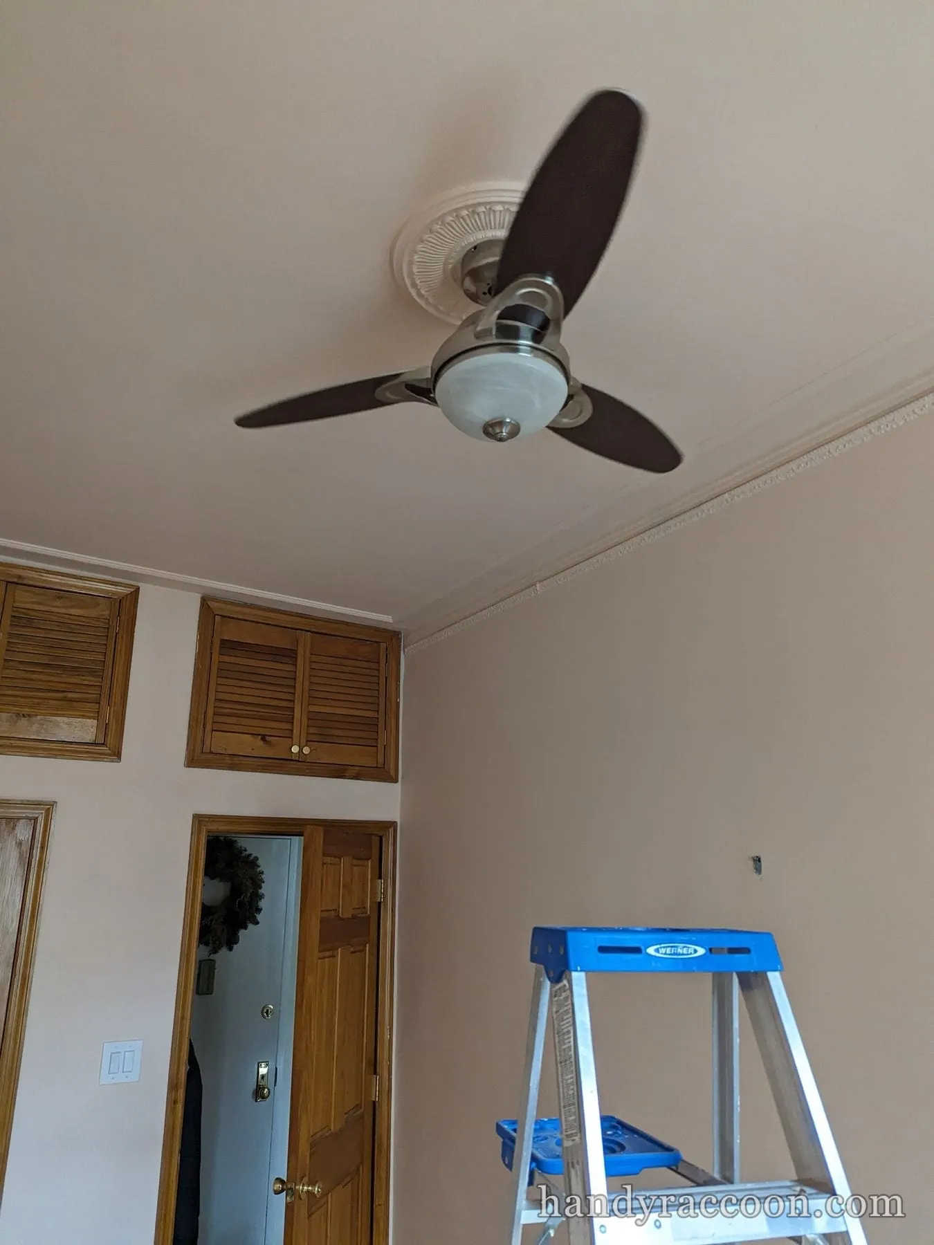 Bronze ceiling fan with three blades and a light kit on a decorative medallion.
