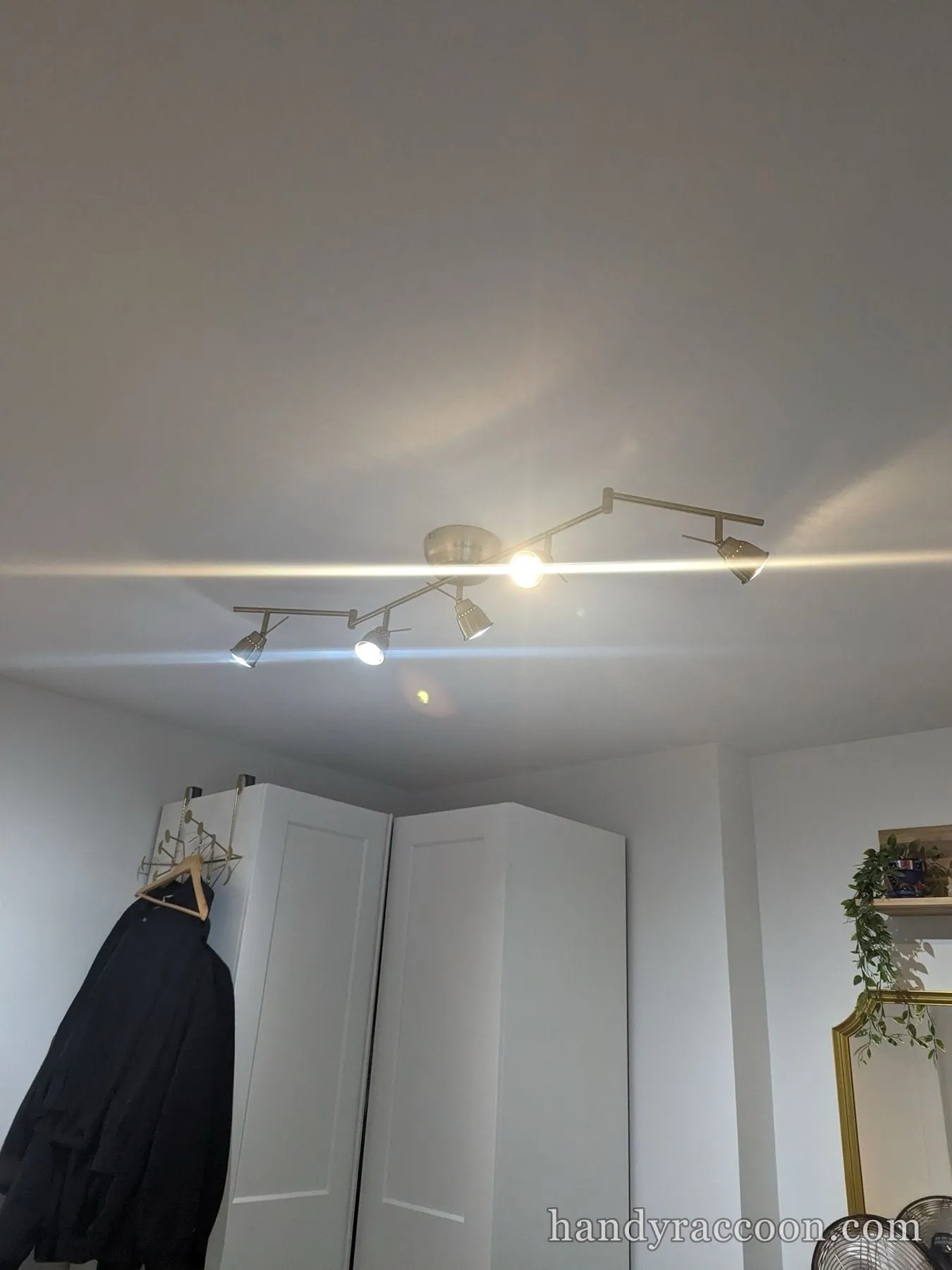 Brushed metal six-spot track light fixture switched on across a ceiling.