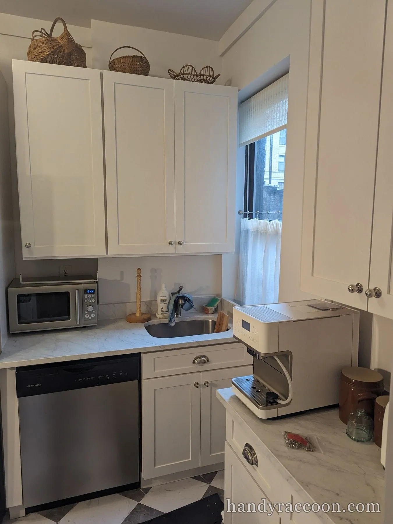 Small kitchen with white cabinets, a stainless dishwasher, sink, and a window.