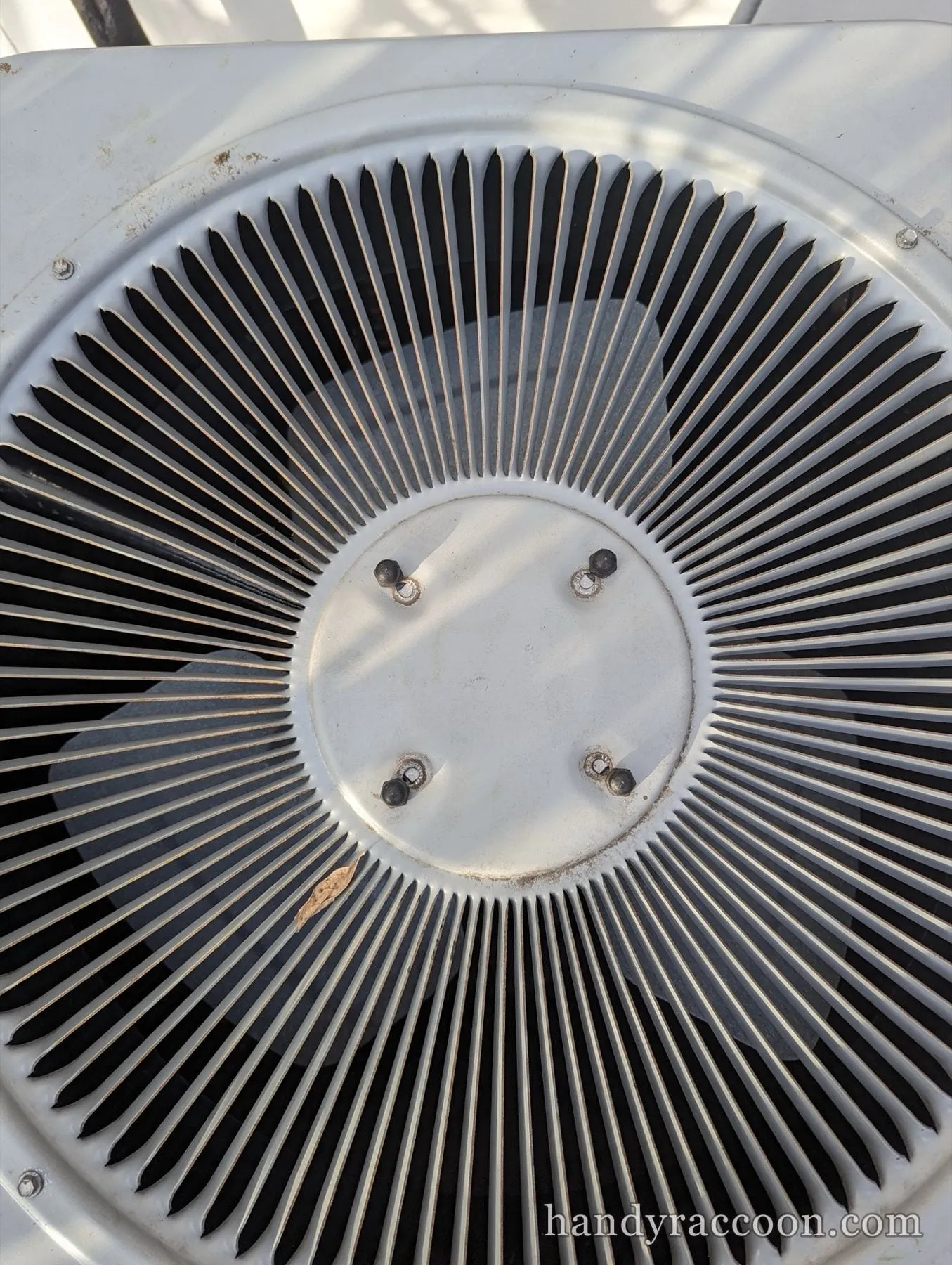Overhead view of the circular fan grille on top of an outdoor AC condenser unit.