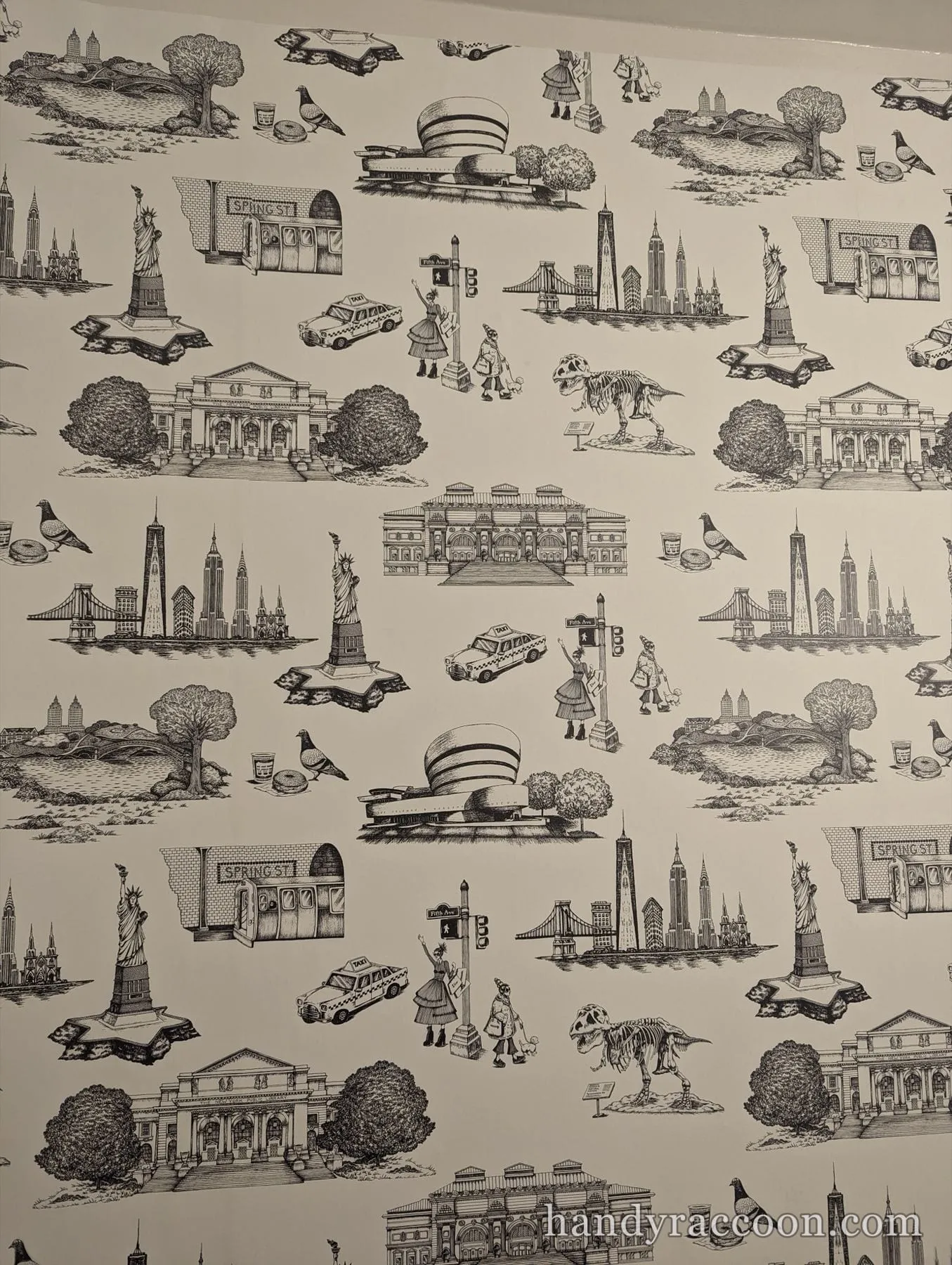 Black-and-white NYC-themed toile wallpaper installed on a wall, showing landmarks, taxis, and skylines.