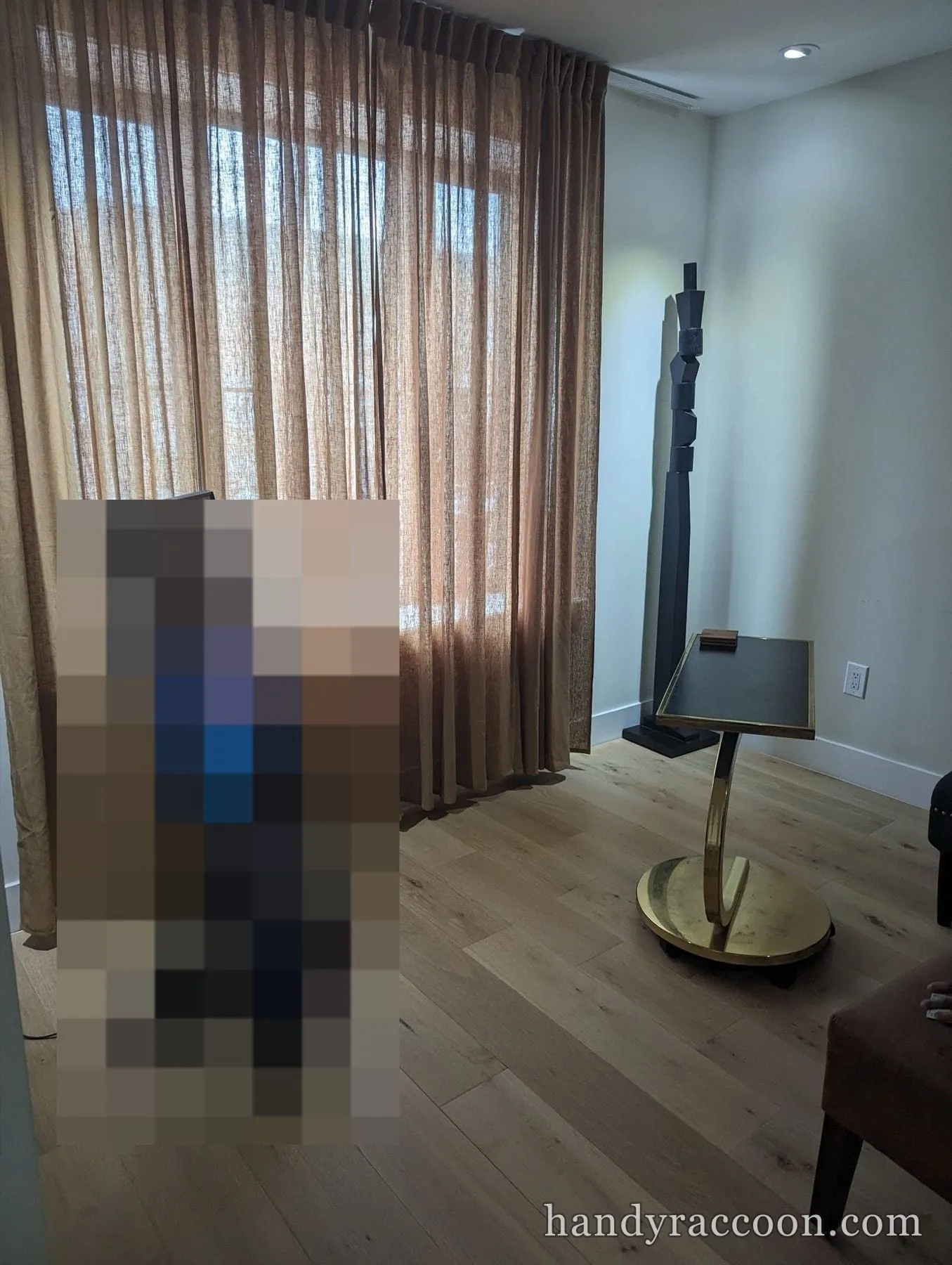 Floor to ceiling tan sheer linen curtains installed across a large window in a styled living room.