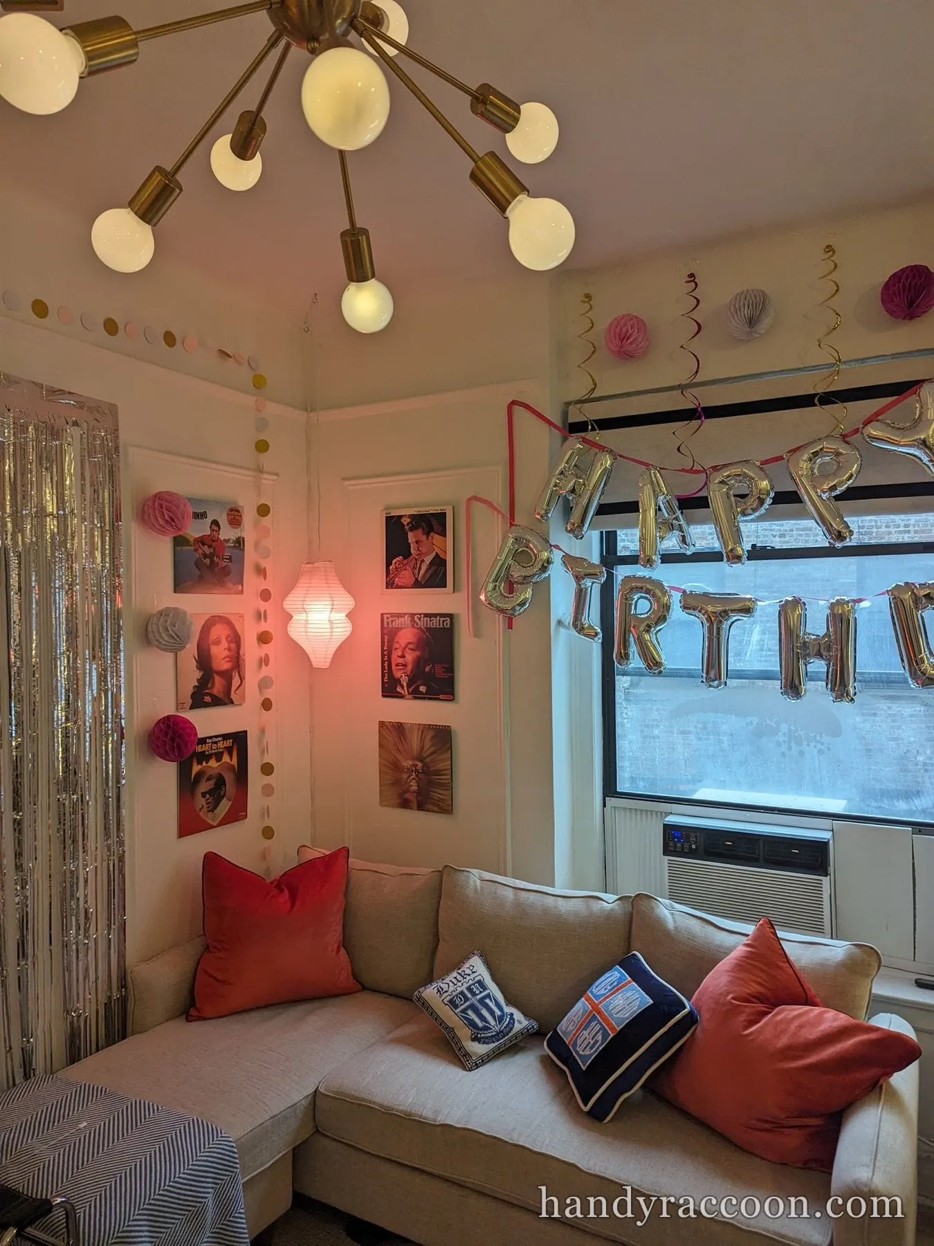 Framed vinyl record covers mounted on a corner wall above a sofa with party decorations.