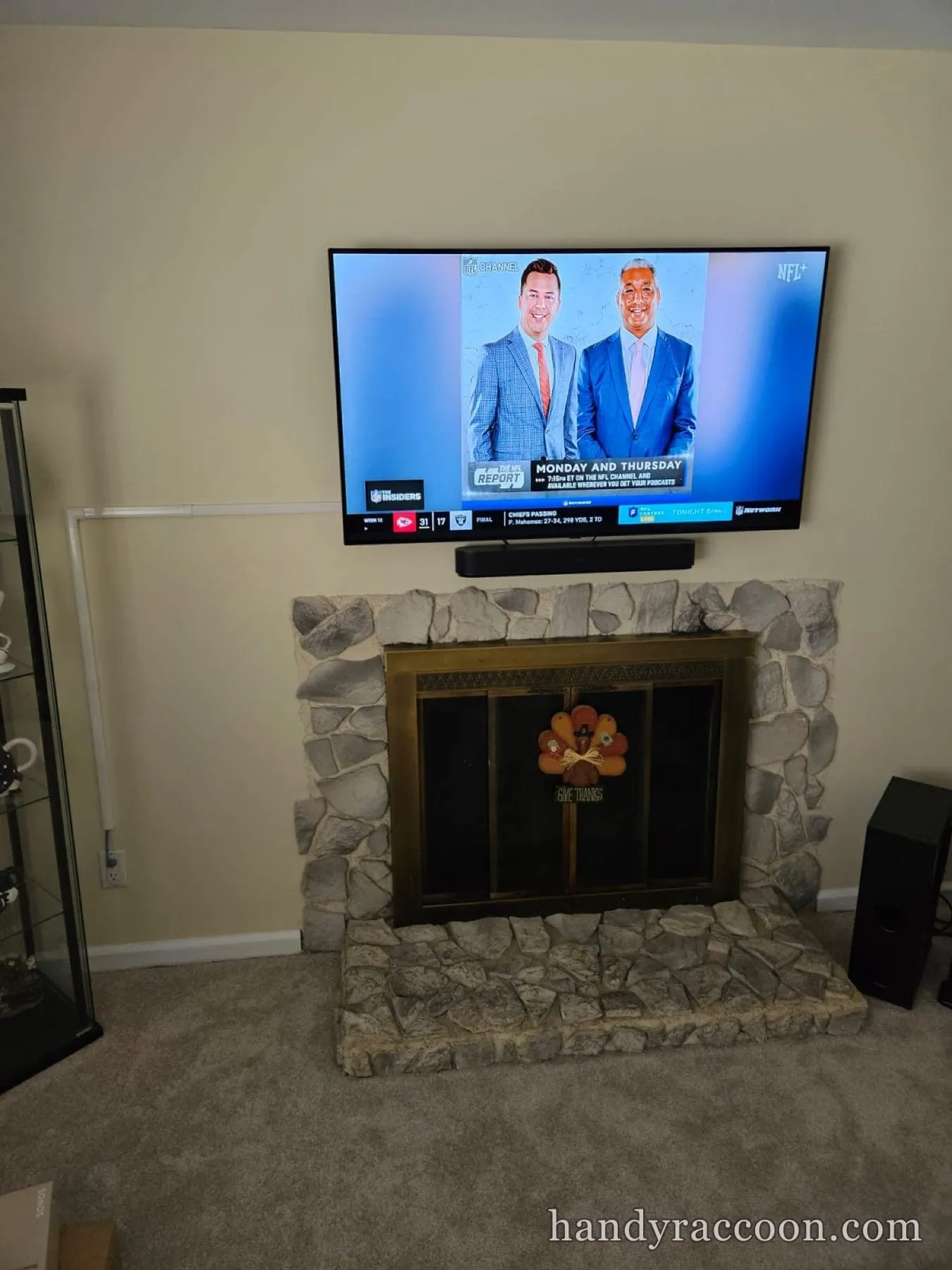 Flat-screen TV mounted on wall above a gray stone fireplace with a black soundbar underneath.