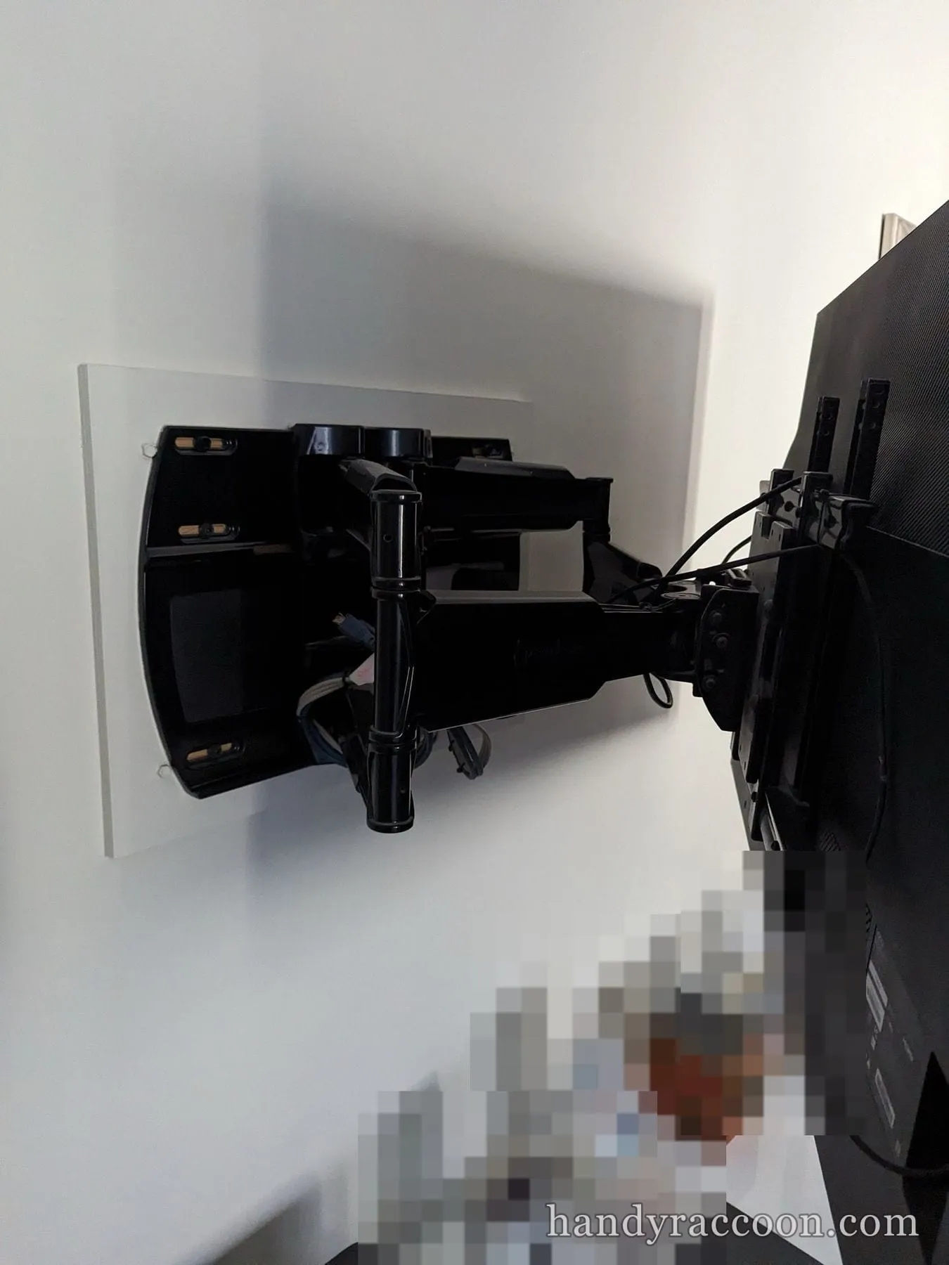 Side view of an extended black articulating TV mount arm holding a television.