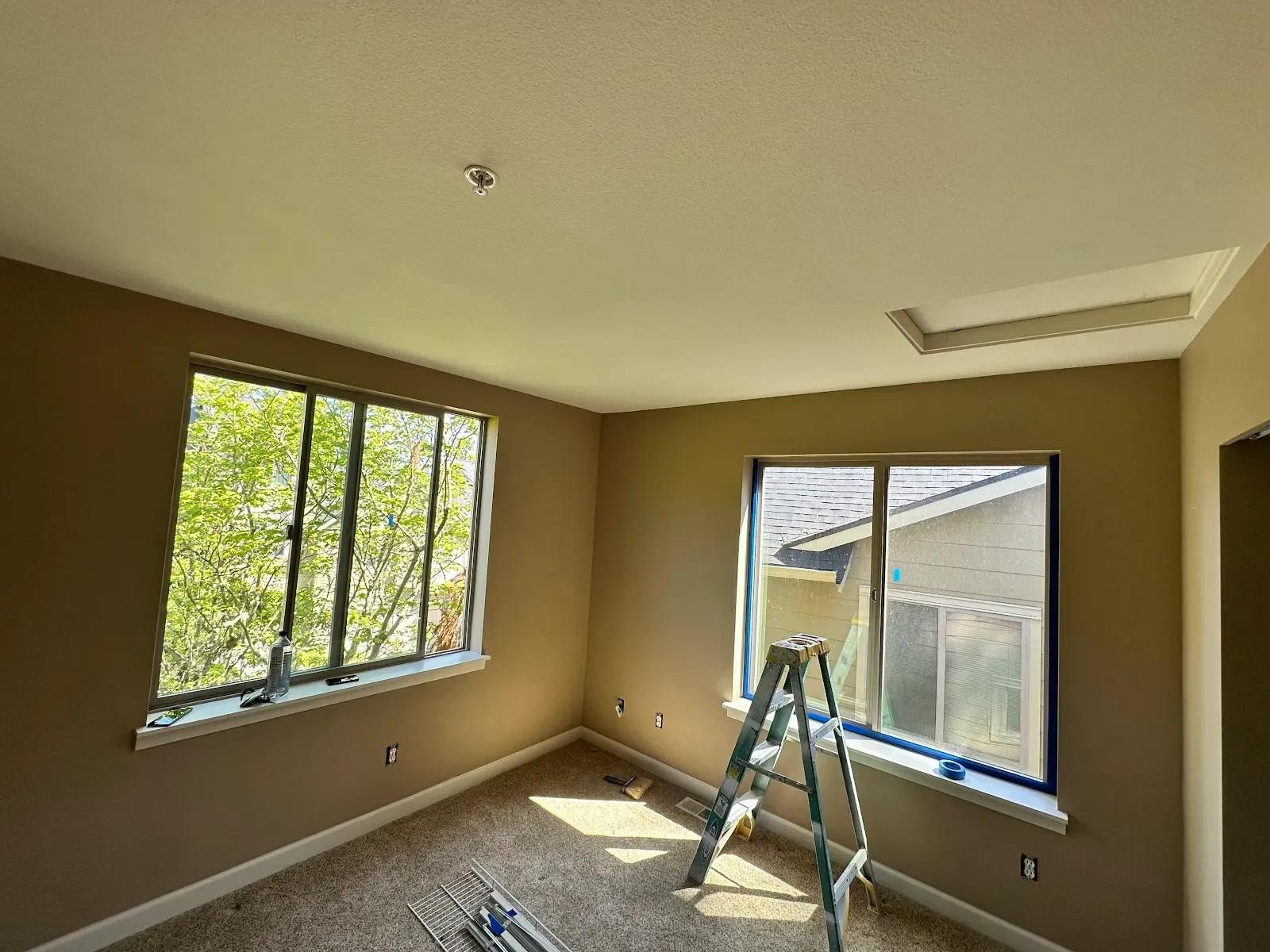 Freshly painted bedroom with taped windows and a stepladder