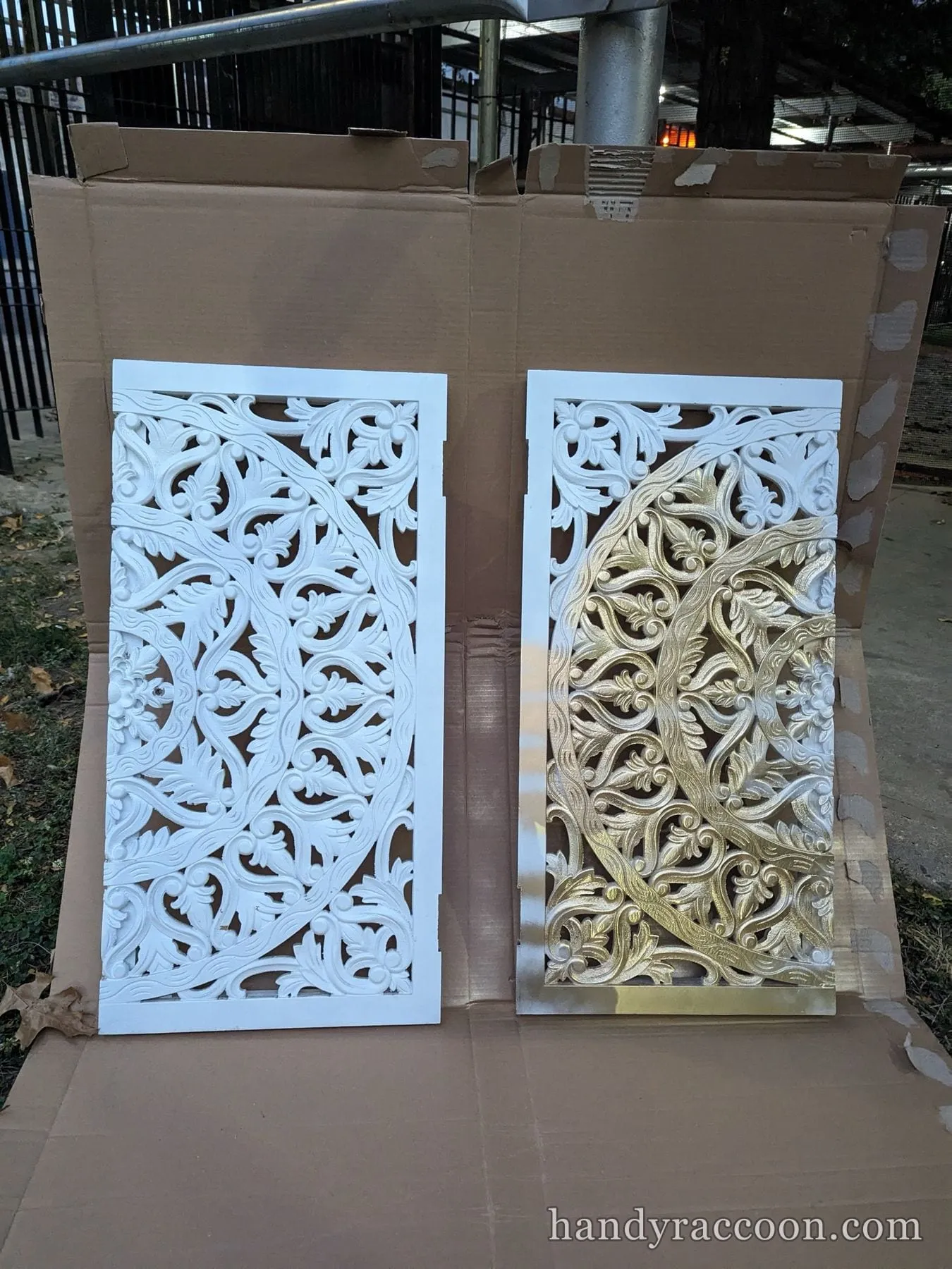 Two ornate carved openwork panels on cardboard outdoors, one white and one gold.