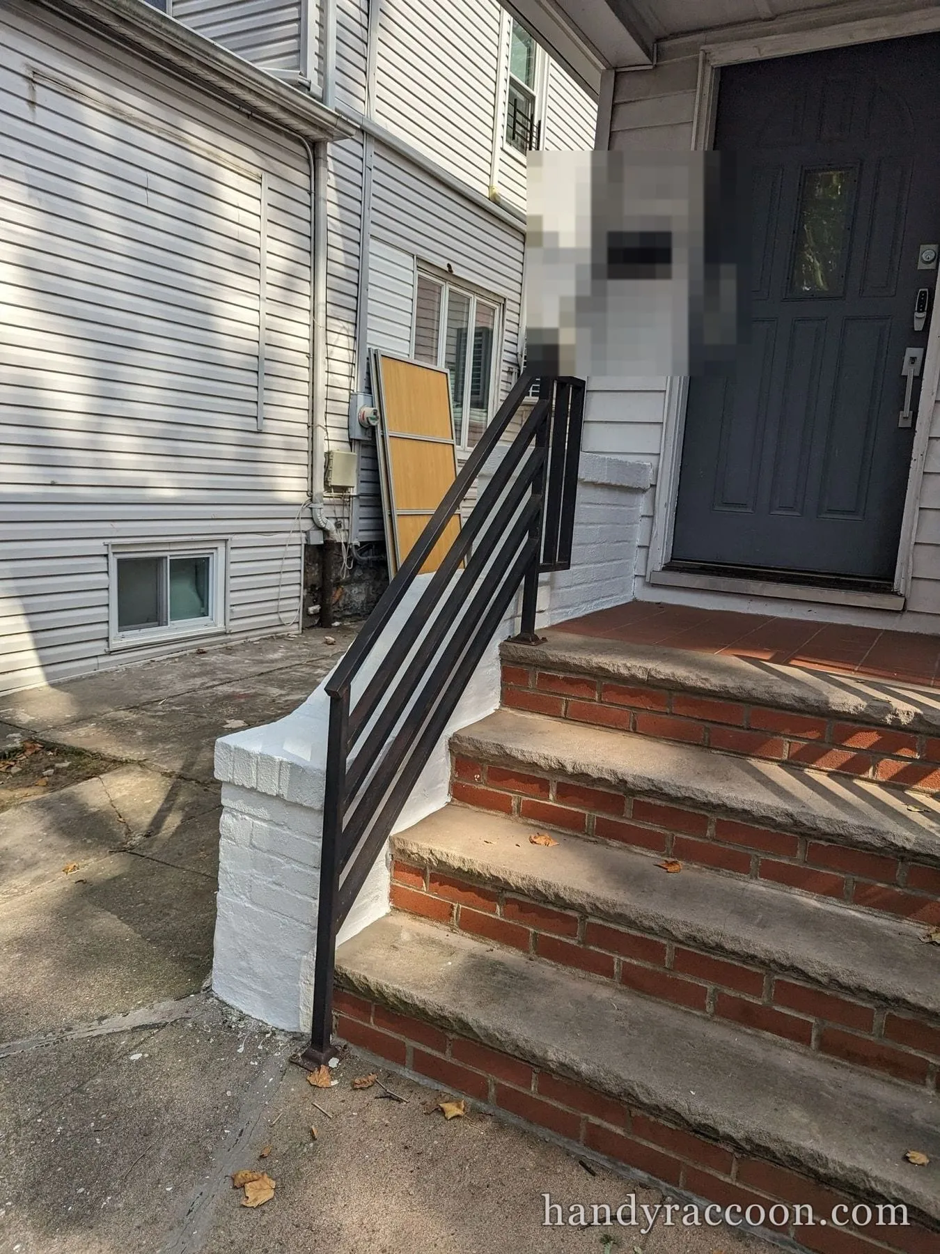 Front stoop with white painted brick piers, black railing and red brick steps.