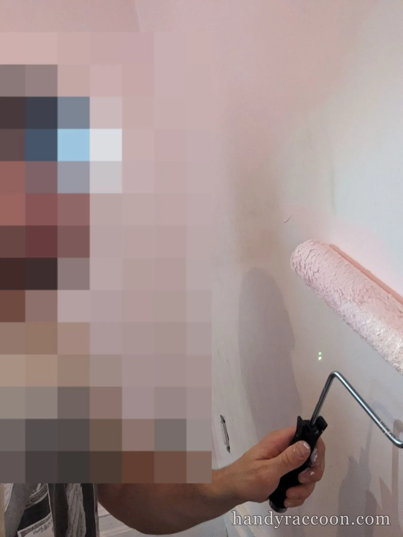 Man with headlamp using a paint roller on a wall during interior painting.