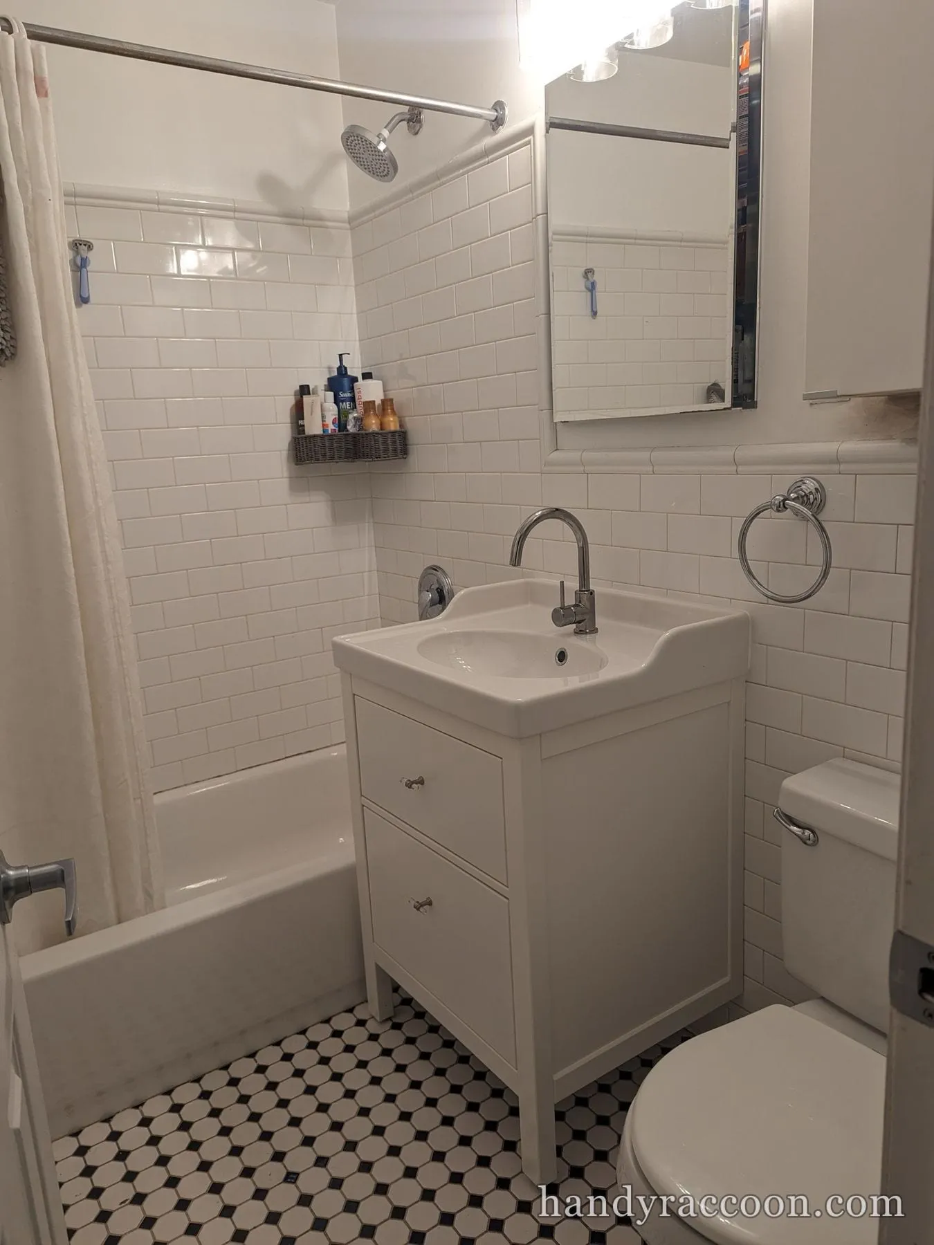 Small bathroom with white sink vanity, chrome faucet, wall mirror, subway tile walls and black-and-white hex floor.