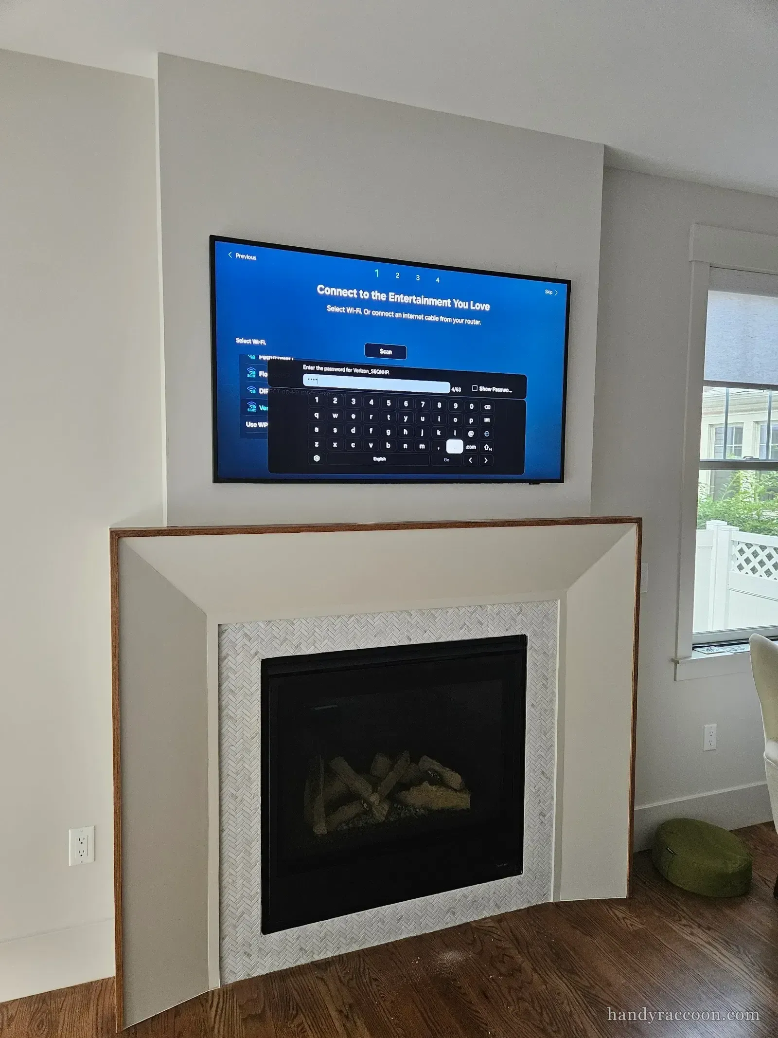 A television mounted flush on the wall above a herringbone-tiled fireplace